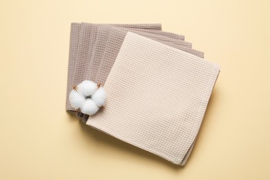 Photo of Clean waffle towels and cotton flower on beige background, top view
