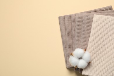 Photo of Clean waffle towels and cotton flower on beige background, top view. Space for text