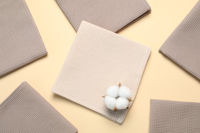 Photo of Clean waffle towels and cotton flower on beige background, flat lay
