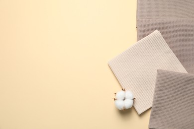 Photo of Clean waffle towels and cotton flower on beige background, flat lay. Space for text
