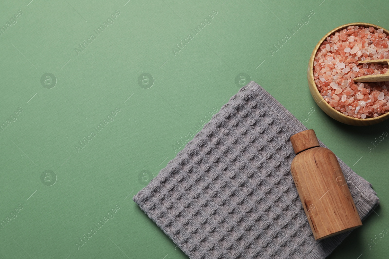 Photo of Clean waffle towel and cosmetic products on green background, flat lay. Space for text