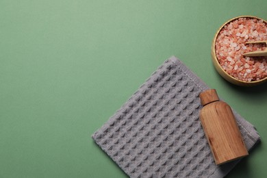 Photo of Clean waffle towel and cosmetic products on green background, flat lay. Space for text