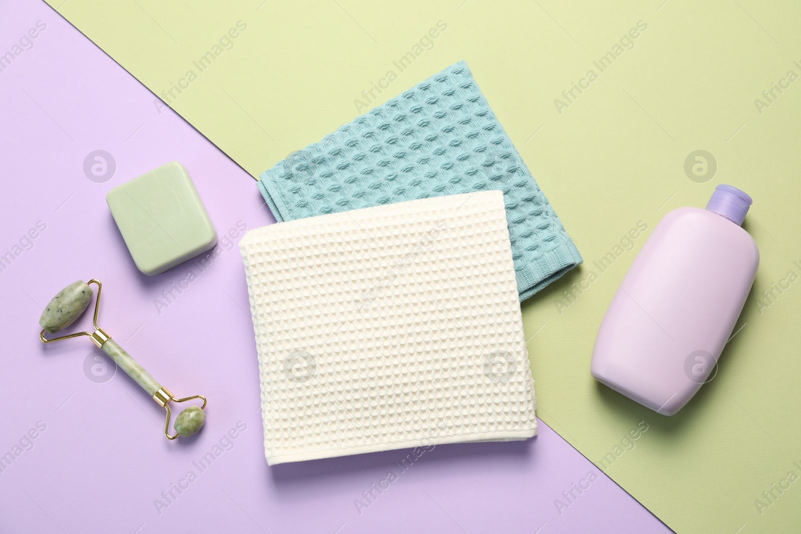 Clean waffle towels and cosmetic products on color background, flat lay Photo of Clean waffle towels and cosmetic products on color background, flat lay