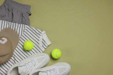 Photo of Sportswear, sneakers and tennis balls on pale olive background, flat lay. Space for text