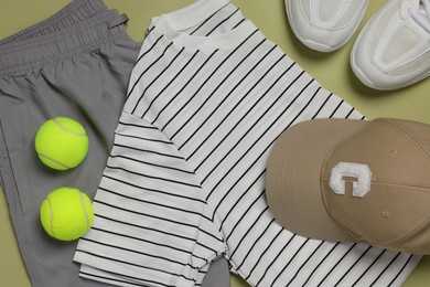 Photo of Sportswear, sneakers and tennis balls on pale olive background, flat lay