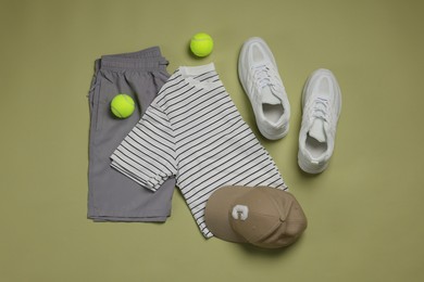 Photo of Sportswear, sneakers and tennis balls on pale olive background, flat lay