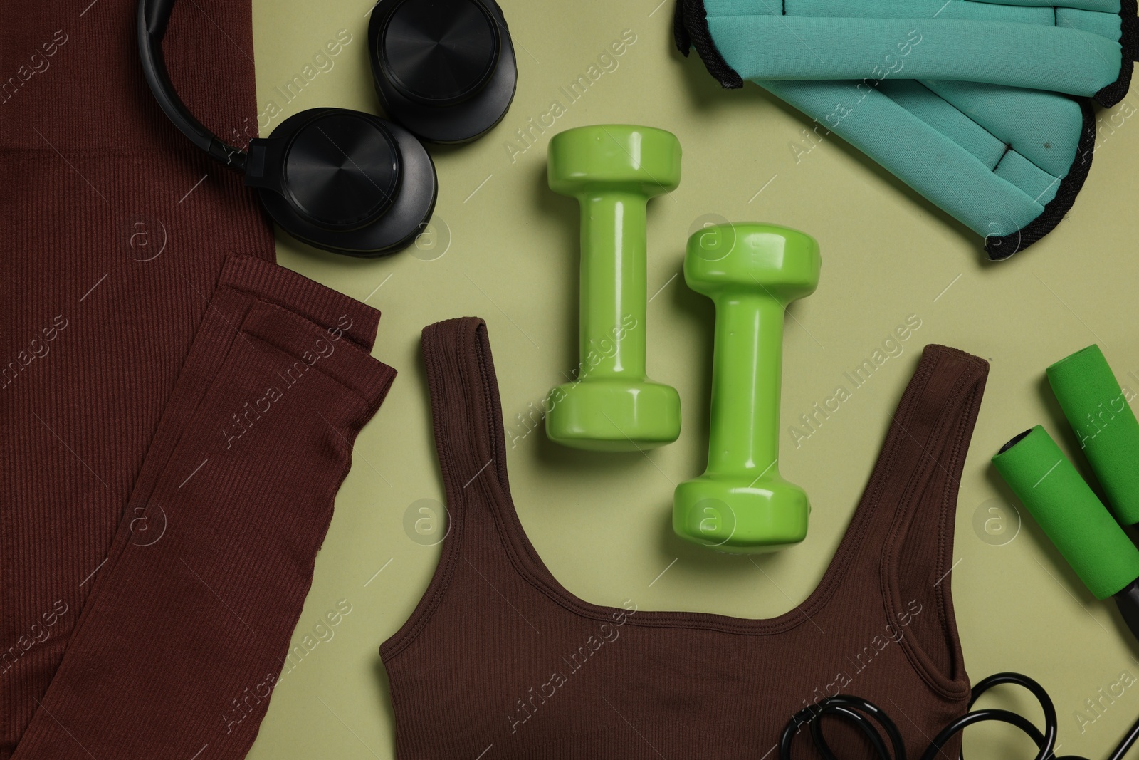 Sportswear, ankle weights, dumbbells, skipping rope and headphones on pale olive background, flat lay Photo of Sportswear, ankle weights, dumbbells, skipping rope and headphones on pale olive background, flat lay