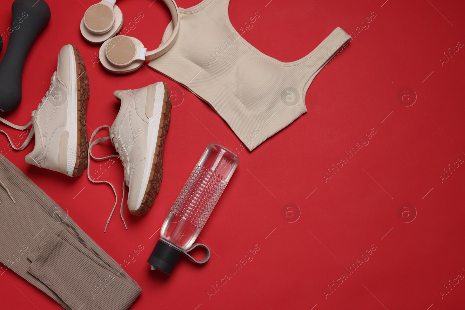 Sportswear, sneakers, dumbbell, headphones and water bottle on red background, flat lay. Space for text Photo of Sportswear, sneakers, dumbbell, headphones and water bottle on red background, flat lay. Space for text