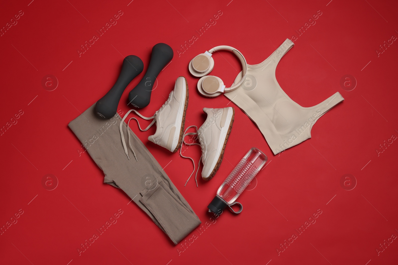 Sportswear, sneakers, dumbbells, headphones and water bottle on red background, flat lay Photo of Sportswear, sneakers, dumbbells, headphones and water bottle on red background, flat lay