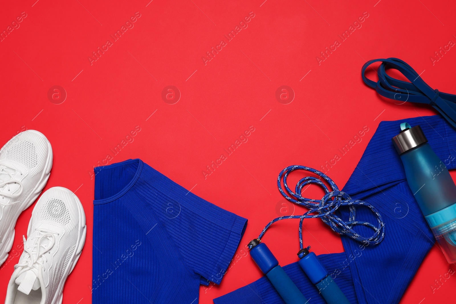 Sportswear, sneakers, skipping rope and water bottle on red background, flat lay. Space for text Photo of Sportswear, sneakers, skipping rope and water bottle on red background, flat lay. Space for text