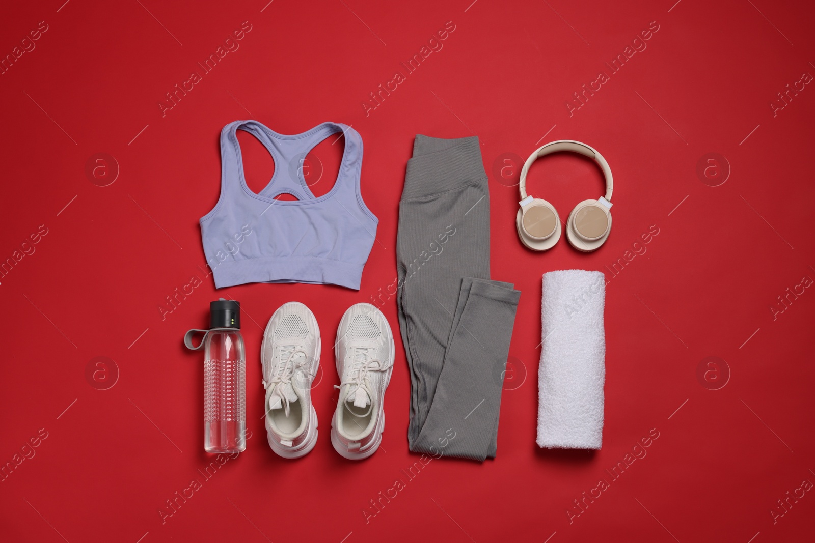 Sportswear, sneakers, towel, headphones and water bottle on red background, flat lay Photo of Sportswear, sneakers, towel, headphones and water bottle on red background, flat lay
