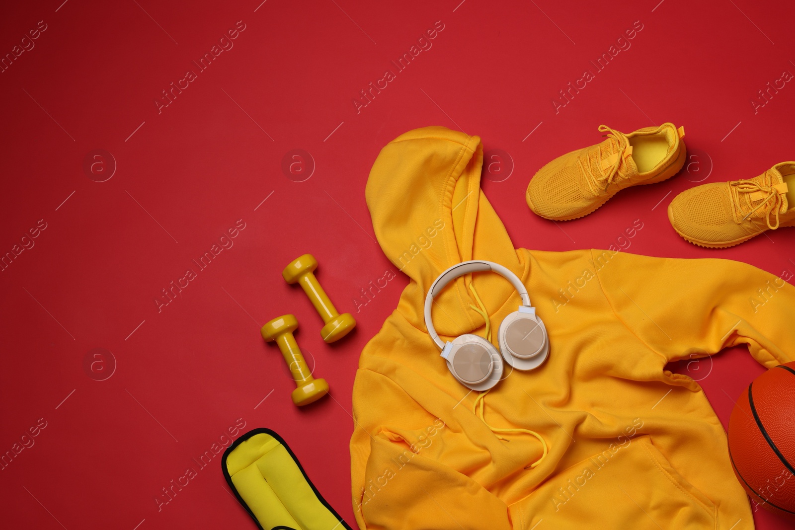 Sportswear, sneakers, dumbbells, headphones and basketball ball on red background, flat lay. Space for text Photo of Sportswear, sneakers, dumbbells, headphones and basketball ball on red background, flat lay. Space for text