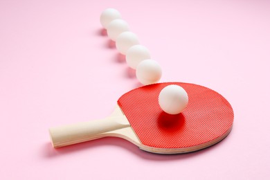 Photo of Ping pong racket and balls on pink background, closeup