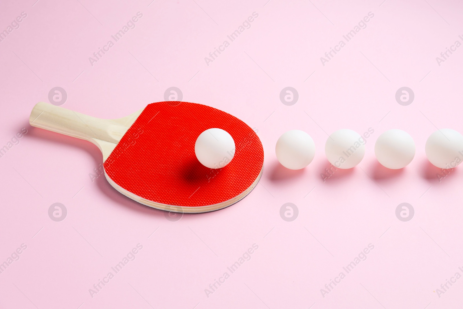 Ping pong racket and balls on pink background Photo of Ping pong racket and balls on pink background