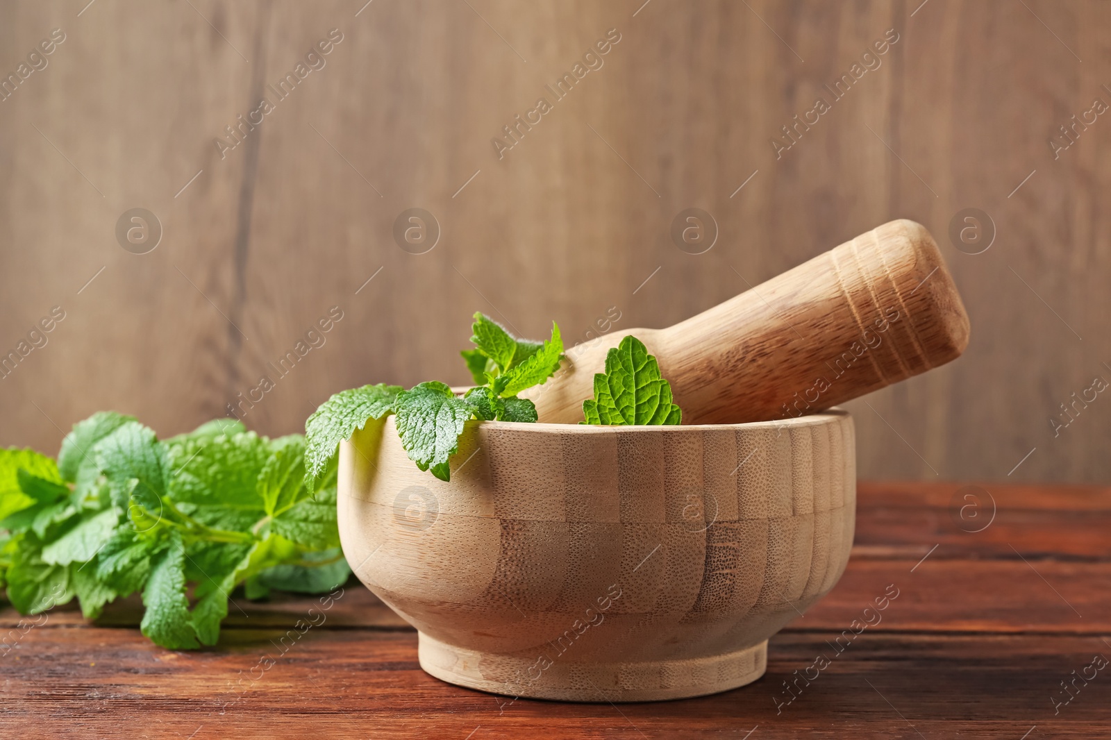 Fresh lemon balm leaves, pestle and mortar on wooden table, closeup Photo of Fresh lemon balm leaves, pestle and mortar on wooden table, closeup