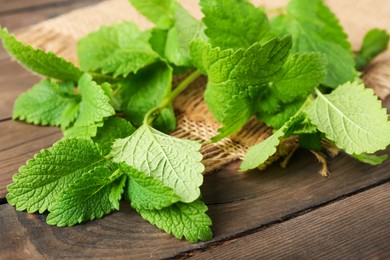 Photo of Fresh lemon balm leaves on wooden table, closeup