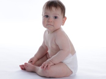 Photo of Cute little baby in diaper sitting on white background