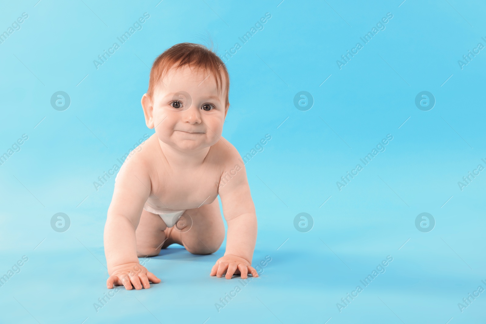 Cute little baby crawling on light blue background. Space for text Photo of Cute little baby crawling on light blue background. Space for text