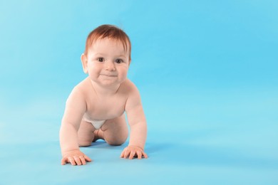 Photo of Cute little baby crawling on light blue background. Space for text