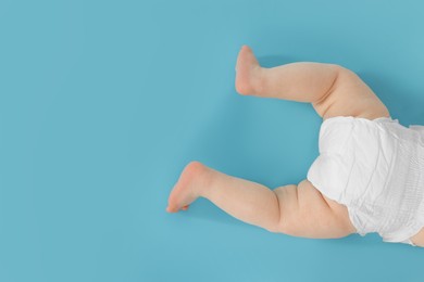 Photo of Cute little baby crawling on light blue background, top view. Space for text