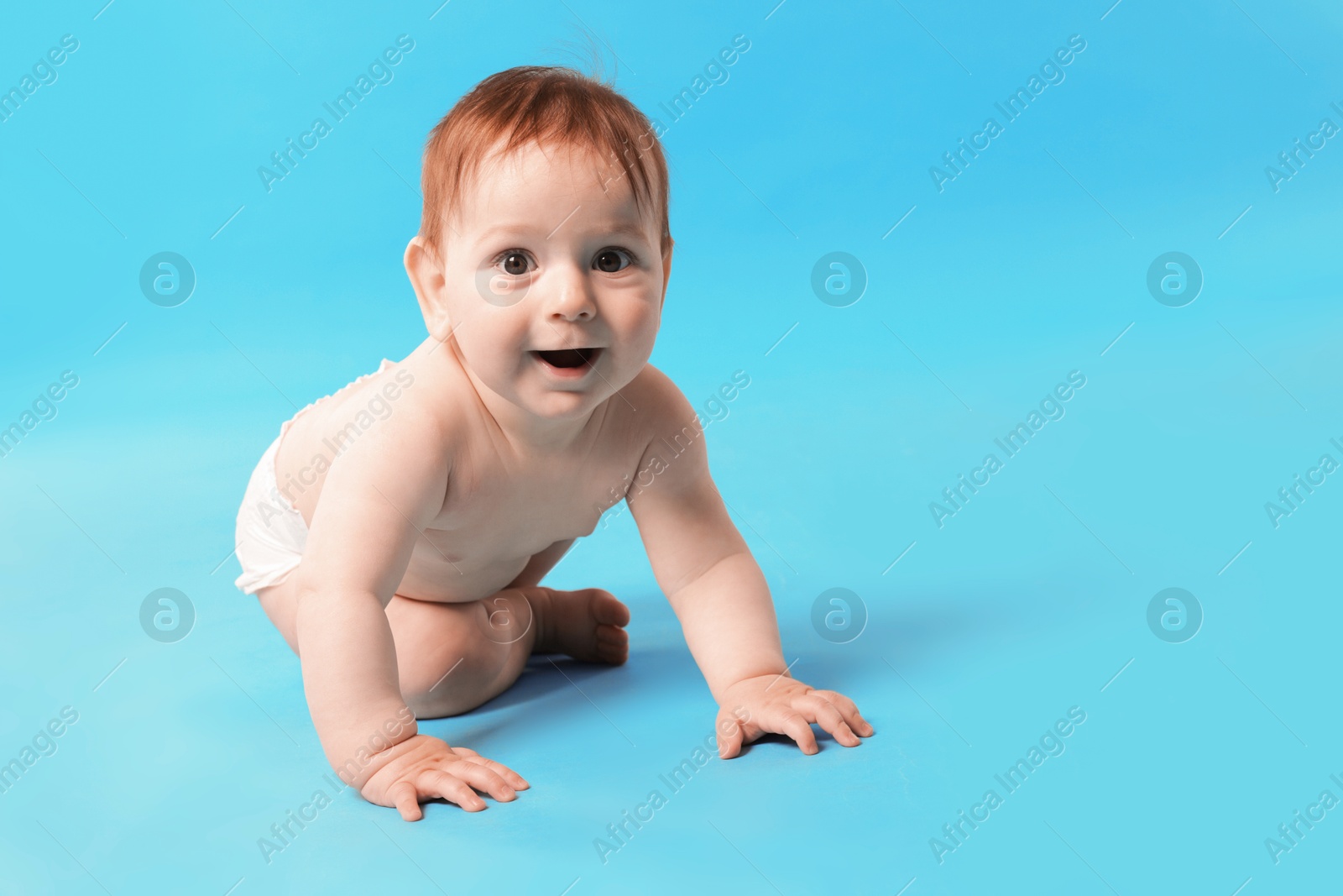 Cute little baby crawling on light blue background Photo of Cute little baby crawling on light blue background