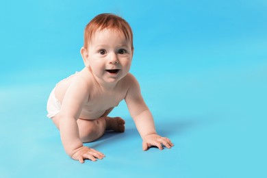 Photo of Cute little baby crawling on light blue background