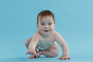 Photo of Cute little baby crawling on light blue background