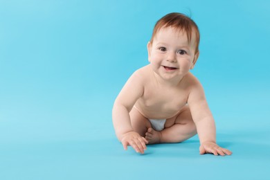 Photo of Cute little baby crawling on light blue background. Space for text