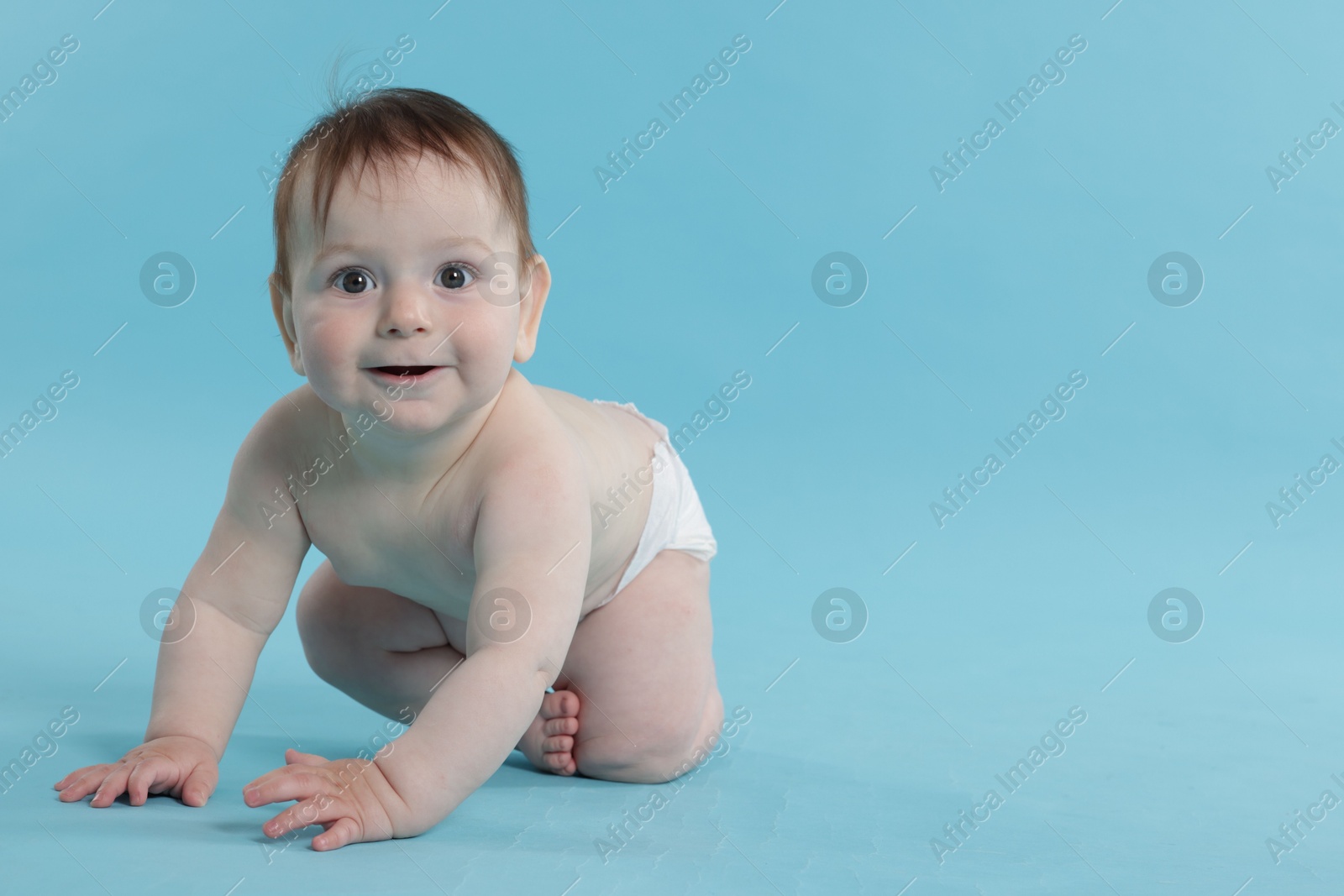 Cute little baby crawling on light blue background. Space for text Photo of Cute little baby crawling on light blue background. Space for text