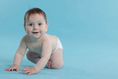 Photo of Cute little baby crawling on light blue background. Space for text