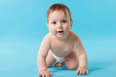 Photo of Cute little baby crawling on light blue background