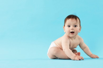 Photo of Cute little baby crawling on light blue background. Space for text