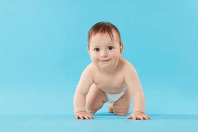 Photo of Cute little baby crawling on light blue background