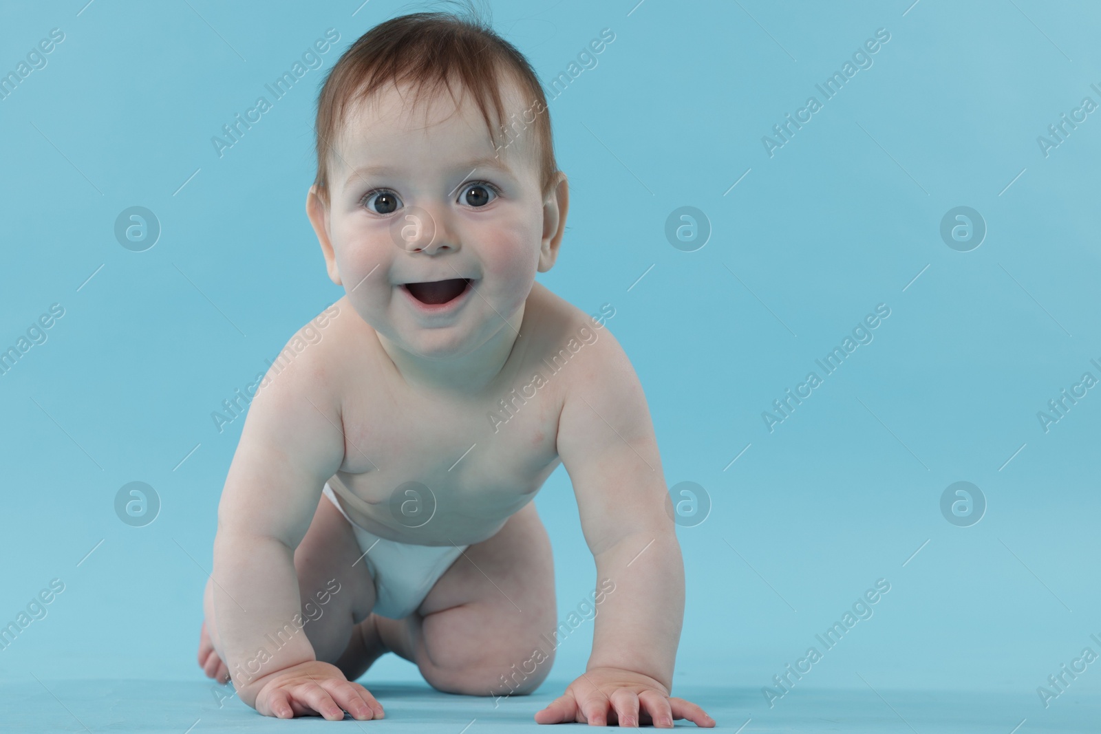 Cute little baby crawling on light blue background Photo of Cute little baby crawling on light blue background