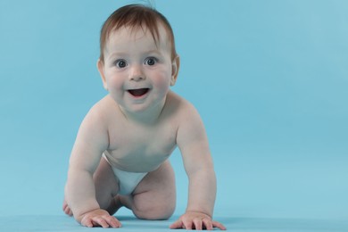 Photo of Cute little baby crawling on light blue background