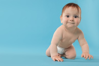 Photo of Cute little baby in diaper sitting on light blue background. Space for text