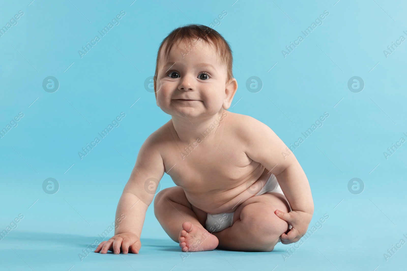 Cute little baby in diaper sitting on light blue background Photo of Cute little baby in diaper sitting on light blue background