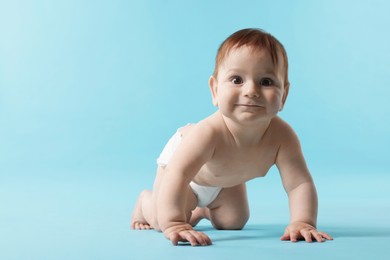 Photo of Cute little baby crawling on light blue background. Space for text