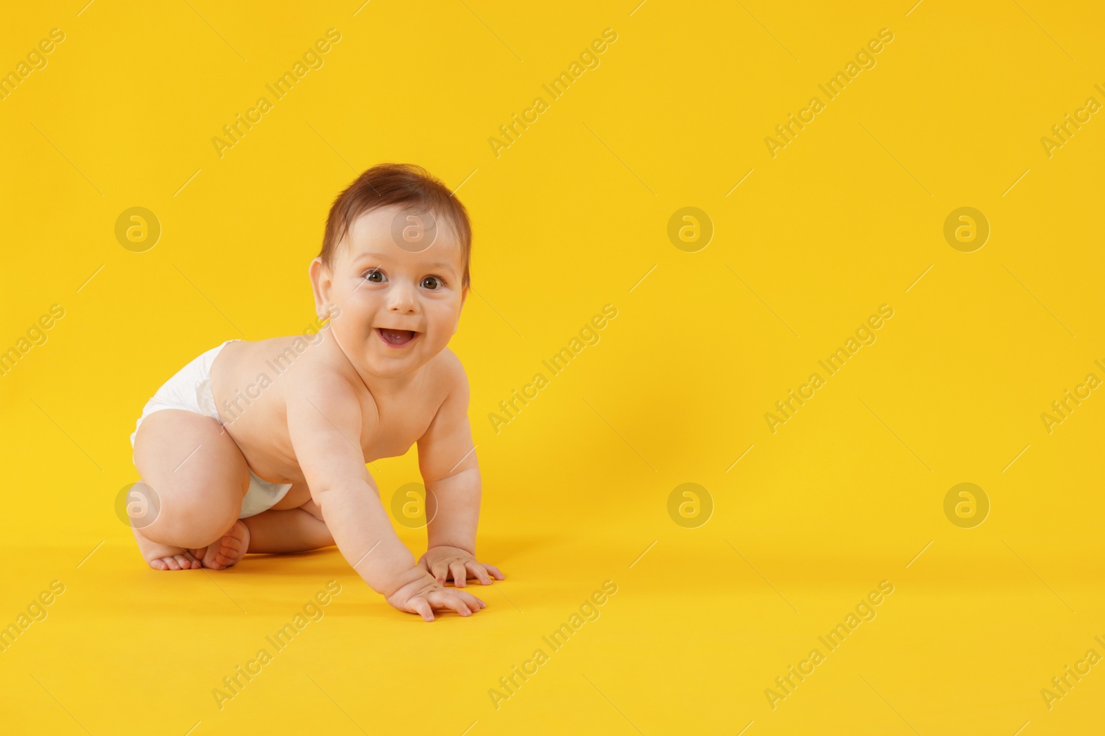 Cute little baby crawling on yellow background. Space for text Photo of Cute little baby crawling on yellow background. Space for text