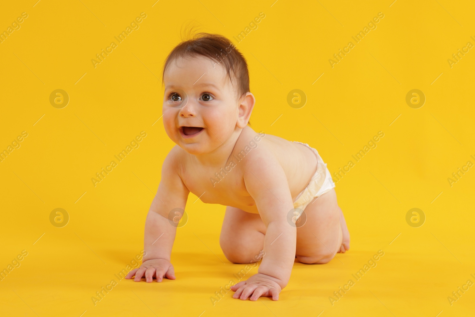 Cute little baby crawling on yellow background Photo of Cute little baby crawling on yellow background
