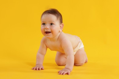Photo of Cute little baby crawling on yellow background