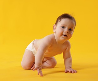 Photo of Cute little baby crawling on yellow background