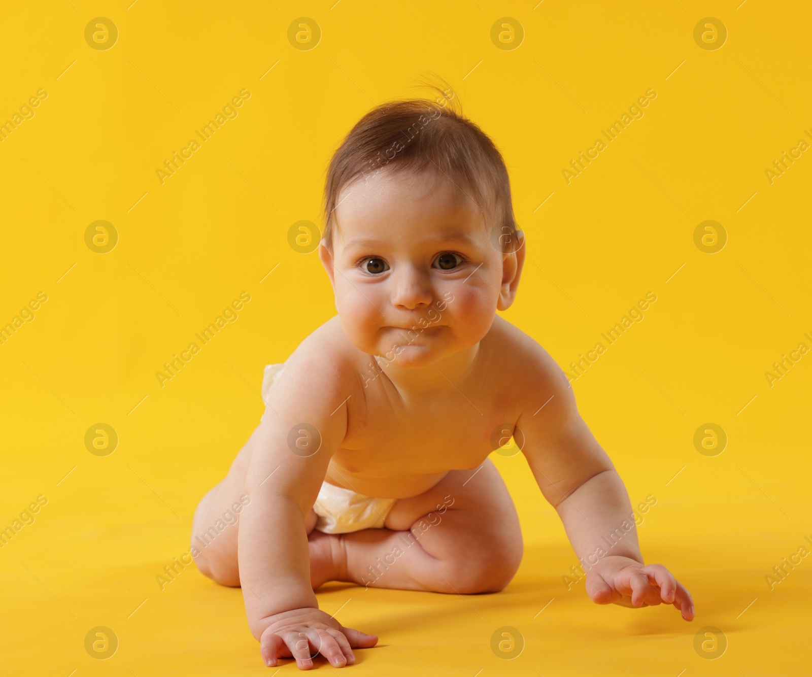 Cute little baby crawling on yellow background Photo of Cute little baby crawling on yellow background