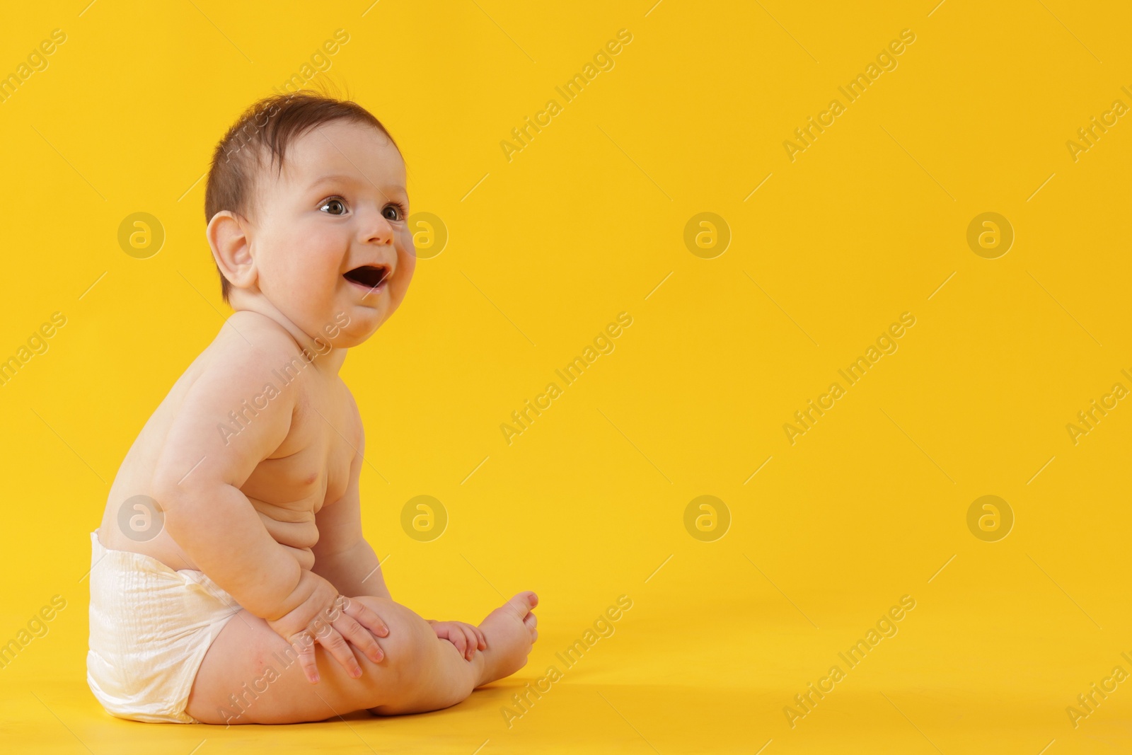 Cute little baby in diaper sitting on yellow background. Space for text Photo of Cute little baby in diaper sitting on yellow background. Space for text