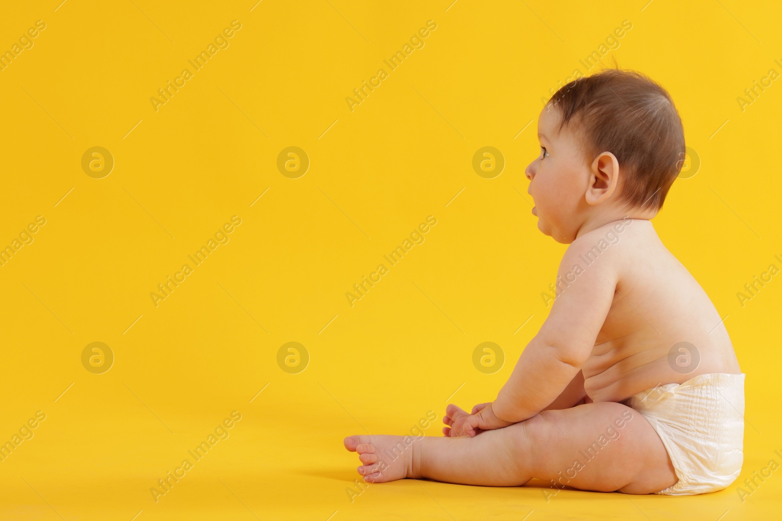 Cute little baby in diaper sitting on yellow background. Space for text Photo of Cute little baby in diaper sitting on yellow background. Space for text