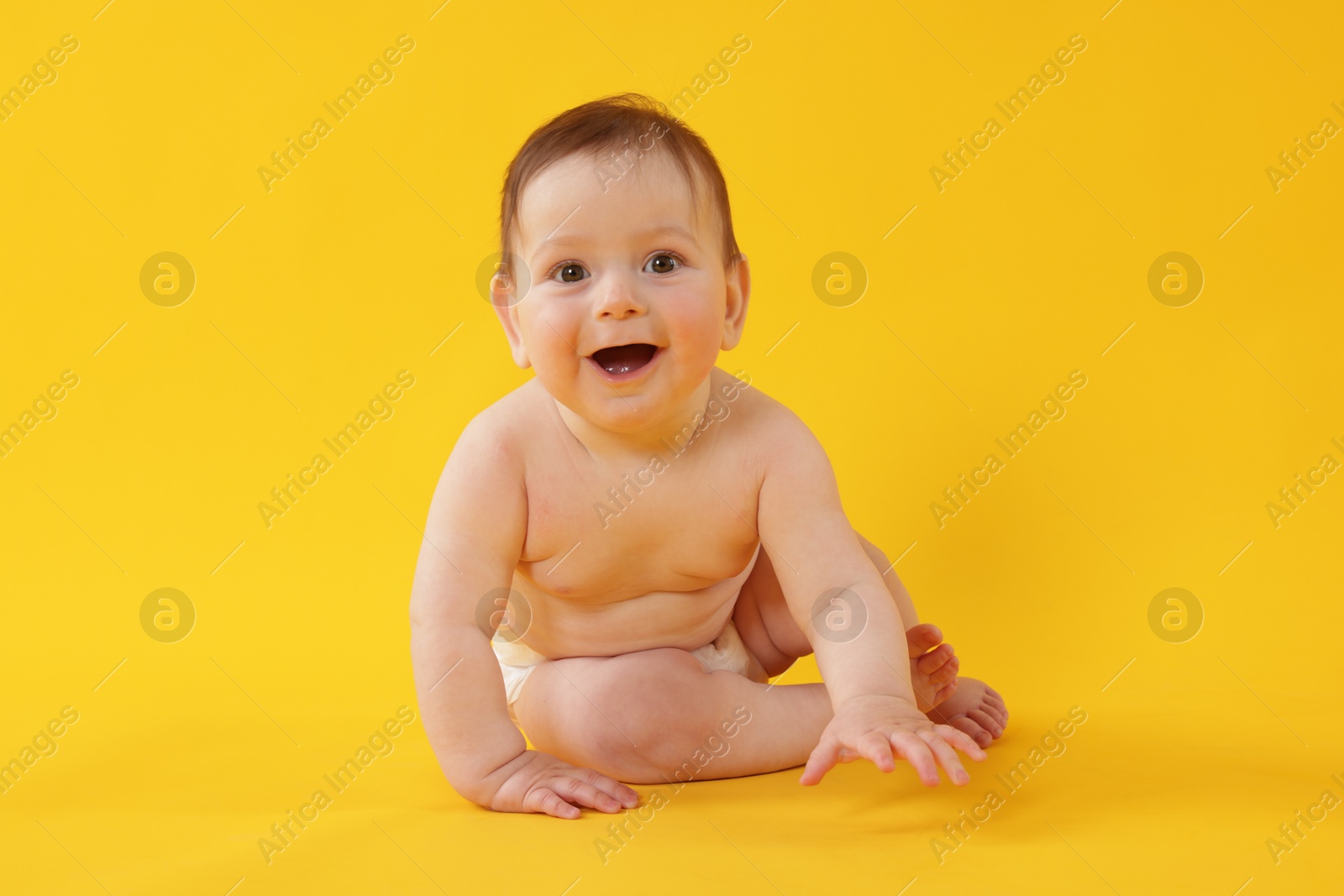 Cute little baby sitting on yellow background Photo of Cute little baby sitting on yellow background