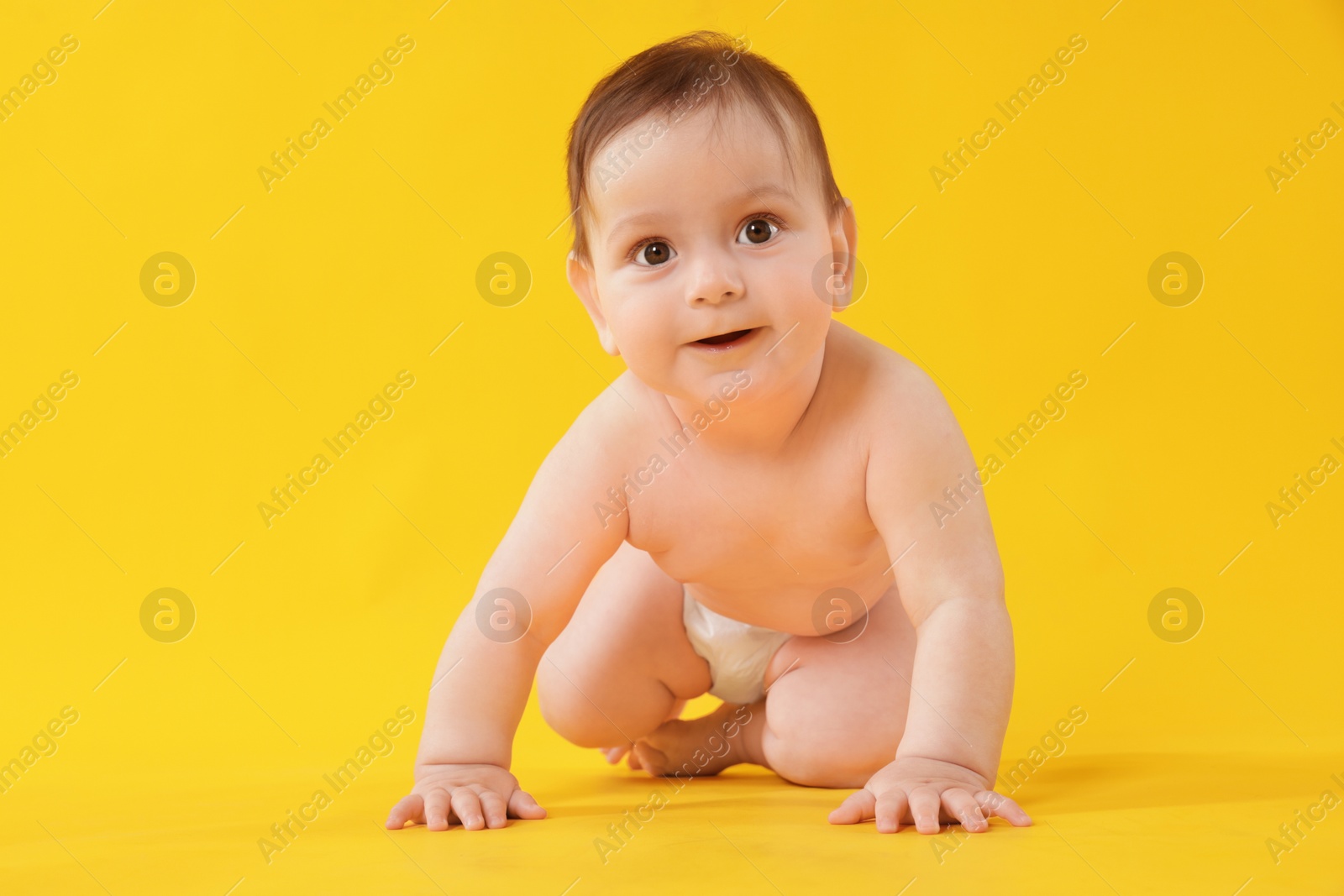 Cute little baby crawling on yellow background Photo of Cute little baby crawling on yellow background