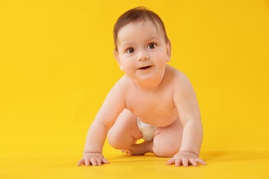 Photo of Cute little baby crawling on yellow background