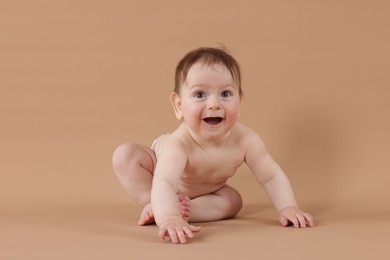Photo of Cute little baby crawling on beige background