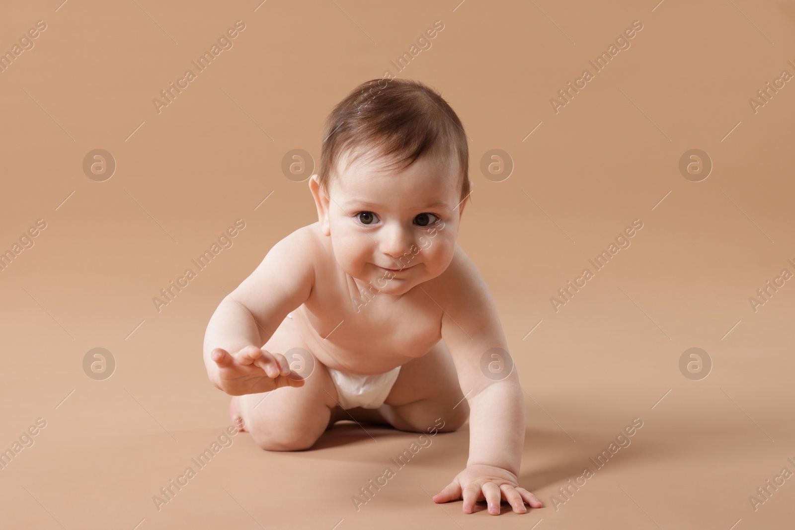 Cute little baby crawling on beige background Photo of Cute little baby crawling on beige background